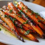 Close-up of glossy, roasted Honey Garlic Butter Roasted Carrots garnished with fresh parsley on a white plate.