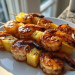 Close-up of grilled Honey Garlic Shrimp Skewers with chunks of caramelized pineapple on a white plate.