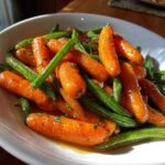 Close-up of vibrant Honey Glazed Carrots and Green Beans coated in a shiny sauce, served in a white bowl.