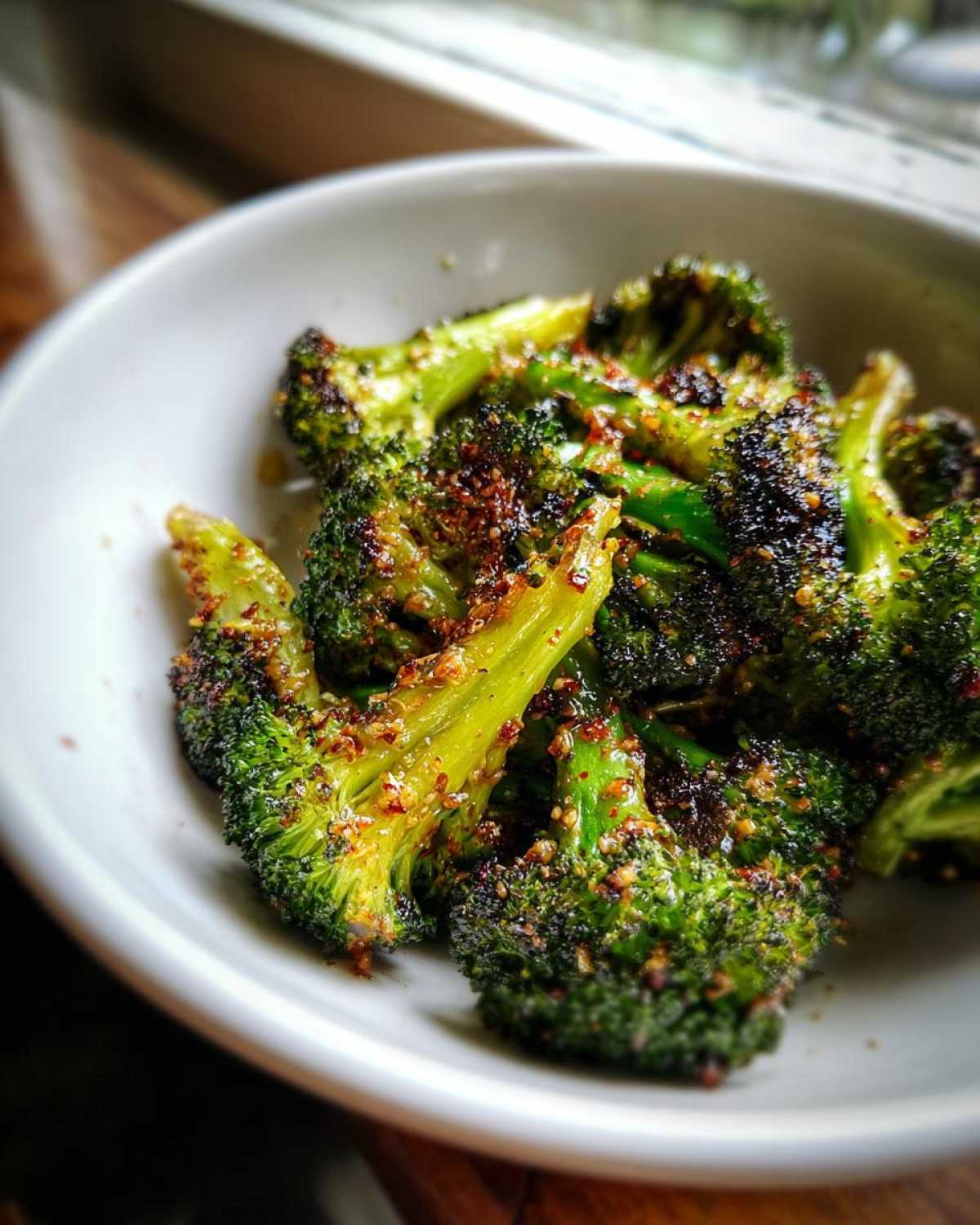 Close-up of perfectly roasted Honey Mustard Roasted Broccoli florets seasoned and served in a white bowl.