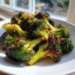 Close-up of vibrant green Honey Mustard Roasted Broccoli florets with caramelized edges on a white plate.