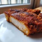 Close-up of a perfectly cooked, juicy air fryer pork chops cut in half, showing the white interior and crispy, seasoned crust.