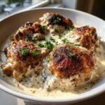 Four perfectly seared chicken thighs smothered in a rich, creamy herb sauce and garnished with fresh parsley.