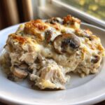 Close-up of a creamy, cheesy serving of keto garlic mushroom chicken casserole on a white plate.