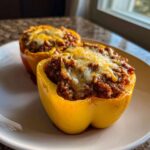 Two halves of yellow Keto Stuffed Bell Peppers filled with seasoned ground meat and topped with melted cheese.