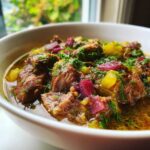 A close-up, tasty shot of rich Khoresh-e Rivas stew featuring chunks of beef, yellow rhubarb, and purple beet pieces, topped with fresh dill.