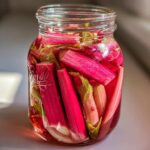 Close-up of bright pink rhubarb stalks packed tightly in a Ball jar for Lacto-Fermented Rhubarb Pickles with Ginger.