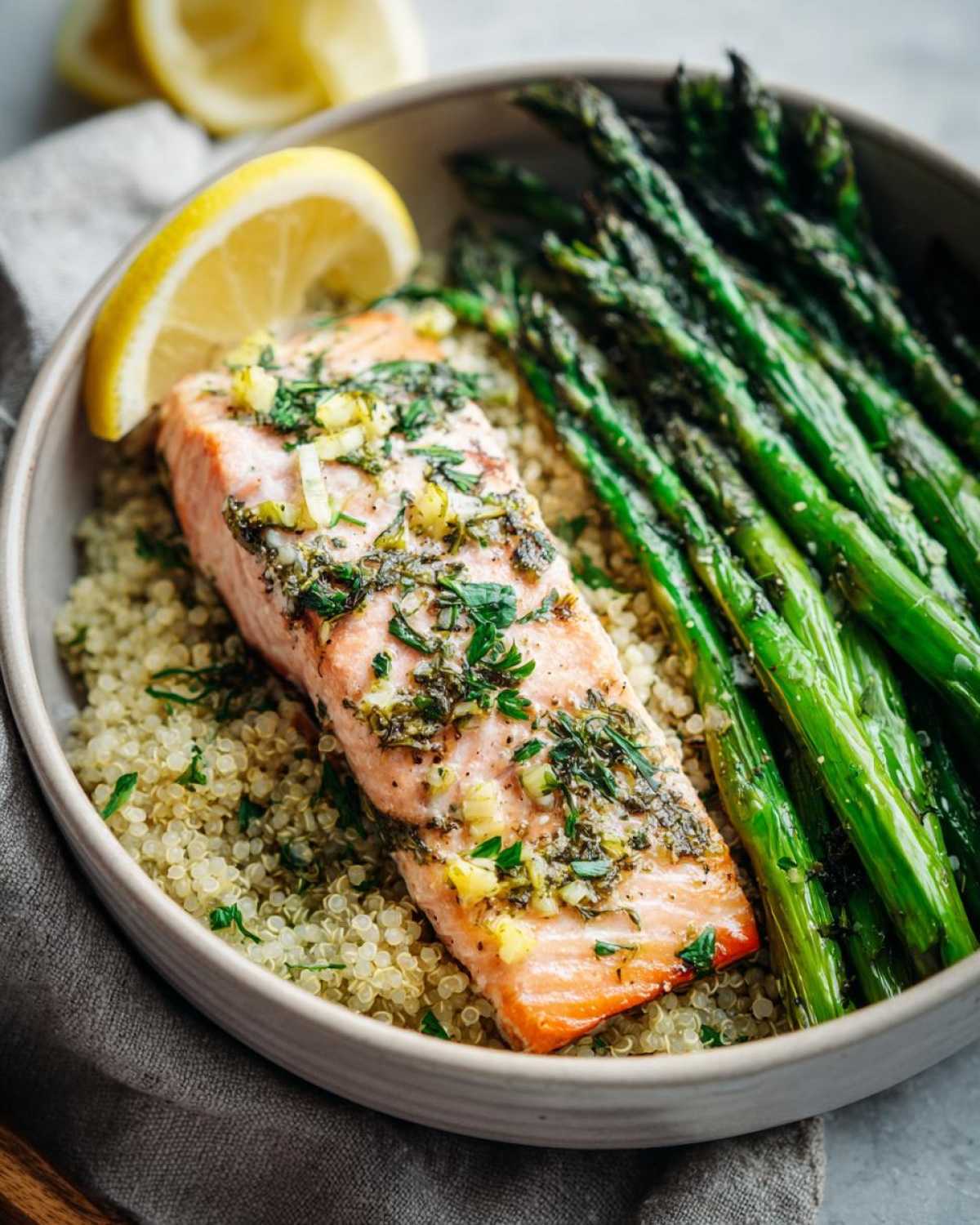 Close-up of a Lemon Herb Roasted Salmon & Asparagus Bowls featuring salmon over quinoa with roasted asparagus.