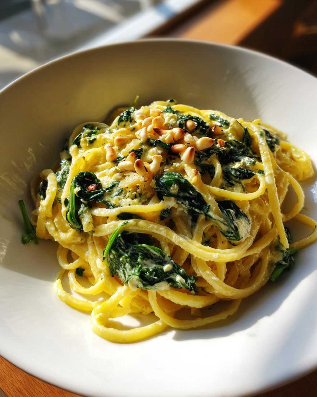 Close-up of Lemon Ricotta Pasta with Spinach tossed in a creamy sauce and topped with toasted pine nuts.