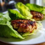 Close-up of a perfectly seared Lettuce Wrap Turkey Burger resting in crisp green lettuce cups.