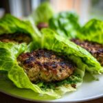 Close-up of three grilled Lettuce Wrap Turkey Burgers served in crisp green lettuce cups on a white plate.