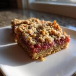 A single square serving of Low-Carb Rhubarb Dream Bars (Almond) with a crumbly topping, sitting on a white plate.