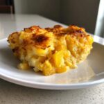 A close-up serving of cheesy, baked low-carb squash casserole with visible chunks of yellow squash.