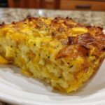 A close-up of a square serving of baked Low-carb squash casserole with a golden, cheesy, browned top, served on a white plate.