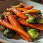Close-up of roasted baby carrots and Brussels sprouts coated in a shiny Maple Glazed Carrots and Brussels Sprouts glaze.