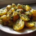 Close-up of warm, halved potatoes coated in a vibrant dressing with fresh dill, perfect for Marinated Potato Salad.