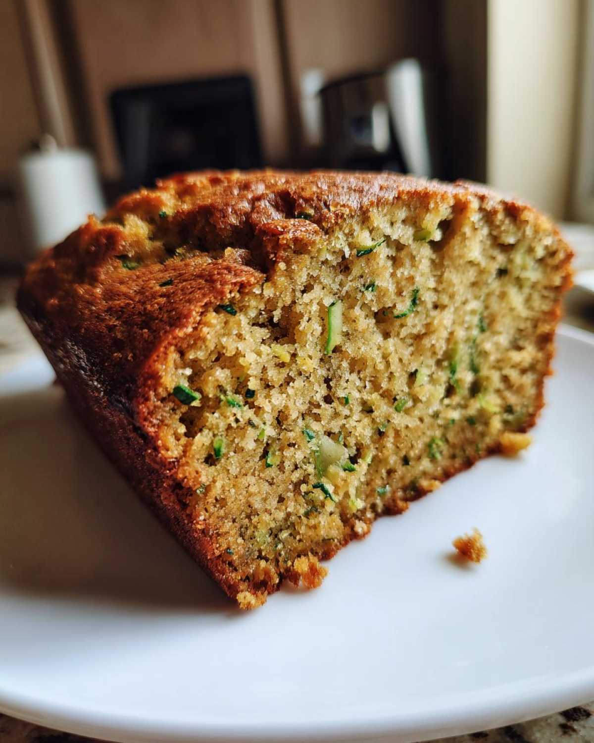 Close-up of a moist slice of homemade zucchini bread recipe showing green shreds of zucchini in the crumb.