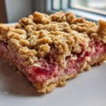 Close-up of a square slice of Old-Fashioned Rhubarb Crunch showing the thick, gooey rhubarb filling and oat crumble topping.