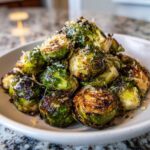 A mound of perfectly cooked Oven Roasted Brussels Sprouts with Parmesan cheese sprinkled on top.