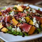 A vibrant Peach & Burrata Salad with Prosciutto featuring fresh peaches, torn burrata, and prosciutto drizzled with balsamic glaze.