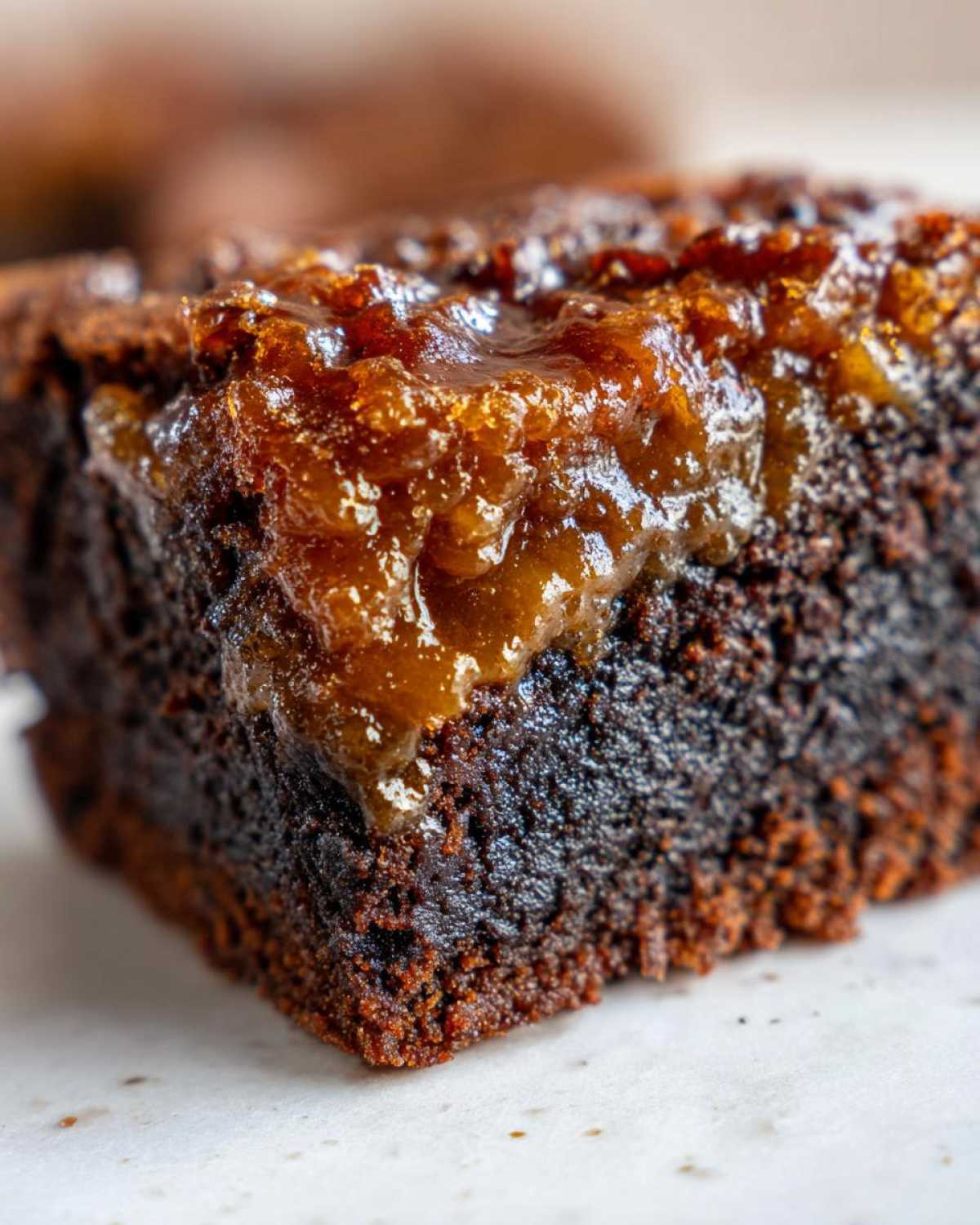 A close-up view of a rich, fudgy pecan pie brownies square topped with a thick, glossy layer of pecan pie filling.