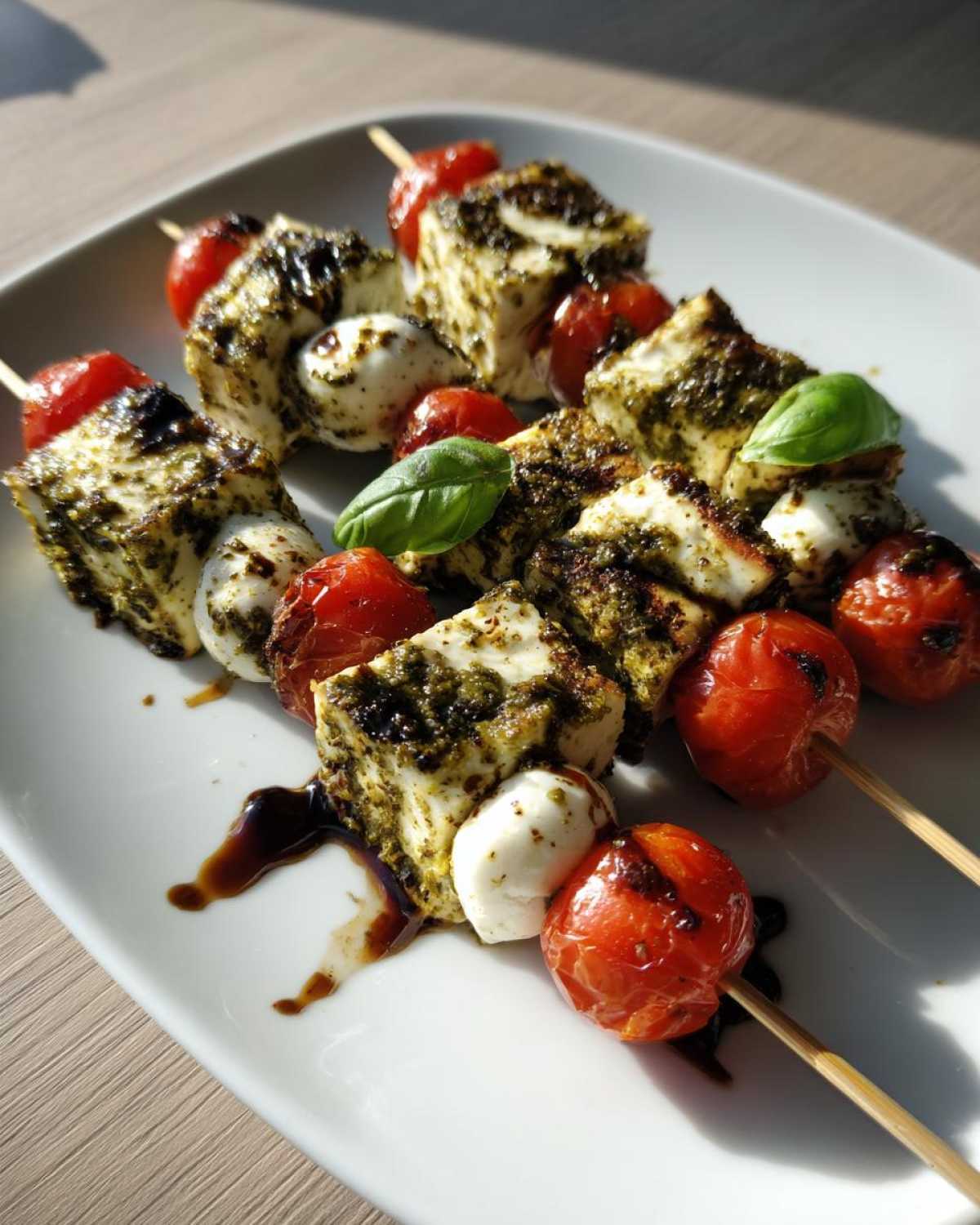 Close-up of Pesto Chicken Caprese Skewers featuring grilled chicken cubes, mozzarella balls, and blistered tomatoes.