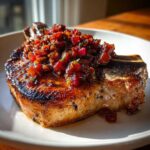 A perfectly seared, thick-cut pork chop topped generously with a dark red Ancho Chilli Rhubarb Salsa.