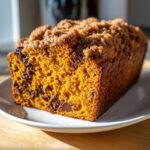 A close-up of a freshly baked Pumpkin Chocolate Chip Streusel Bread loaf with a thick, sugary streusel topping.
