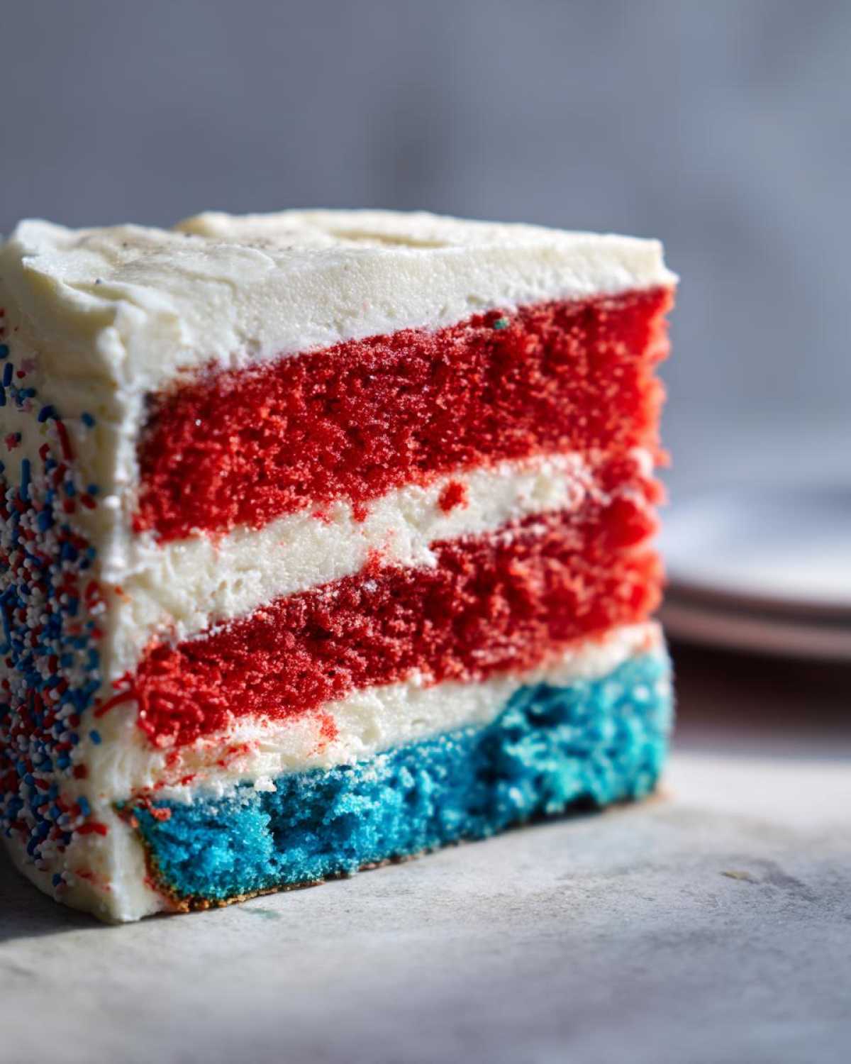Close-up of a slice of Red, White & Blue Layered Flag Cake showing red, white, and blue layers with white frosting.