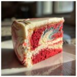 A close-up slice of Red, White & Blue Marble Memorial Day Cake showing red, white, and blue swirled layers with white frosting.