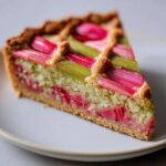Close-up of a slice of Rhubarb and Almond Chevron Tart showing pink and green rhubarb stalks and almond frangipane filling.