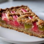 Close-up of a slice of Rhubarb and Almond Chevron Tart showing vibrant pink rhubarb pieces and crumbly almond crust.