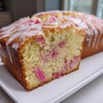 Close-up of a sliced Rhubarb and Earl Grey Tea Loaf showing pink rhubarb pieces baked into the moist crumb, topped with white icing.