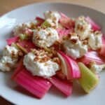 Bright pink and green rhubarb stalks topped with dollops of roasted ricotta and chopped nuts in a Rhubarb Fennel Salad.
