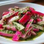 Close-up of vibrant Rhubarb and Fennel Slaw tossed in bright green chimichurri sauce, served in a white bowl.