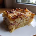 A thick slice of savory Rhubarb-Potato Gratin with Gruyère showing layered potatoes and pink rhubarb pieces.