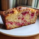 Close-up of a moist slice of Rhubarb Sour Cream Cake with Nutmeg, showing pink rhubarb pieces throughout the crumb.