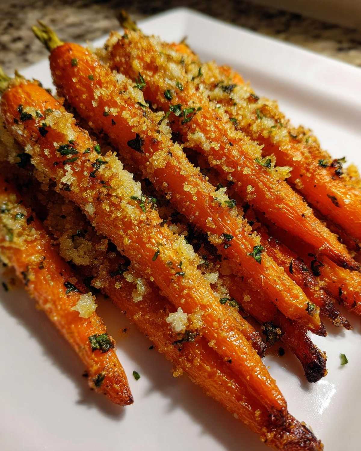 Close-up of perfectly Roasted Parmesan Garlic Carrots, bright orange and topped with crispy breadcrumbs and parsley.