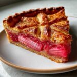 Close-up of a slice of Rustic Geometric Rhubarb Galette showing bright pink rhubarb stalks and golden, flaky crust.