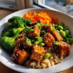 Close-up of Sesame Ginger Tofu Bowls featuring glazed tofu cubes over brown rice with broccoli, edamame, and shredded carrots.
