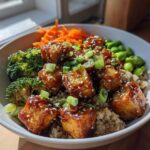 A close-up of vibrant Sesame Ginger Tofu Bowls featuring glazed tofu, brown rice, broccoli, edamame, and shredded carrots.