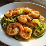 Close-up of plump shrimp served over bright green zucchini noodles in a garlic butter sauce, perfect Shrimp Scampi with Zucchini Noodles.