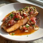 A fillet of Smoked Trout with Brown Butter and Rhubarb topping, garnished with sliced almonds and parsley.