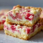 Two stacked squares of Sour Cream Rhubarb Squares with Lemon, showing a thick shortbread crust and creamy filling with bright pink rhubarb pieces.