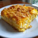 A close-up serving of rich, creamy Southern squash casserole topped with melted cheese and crunchy cornflakes.