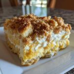 A close-up of a square serving of creamy Southern squash casserole topped with a golden brown crumb topping.