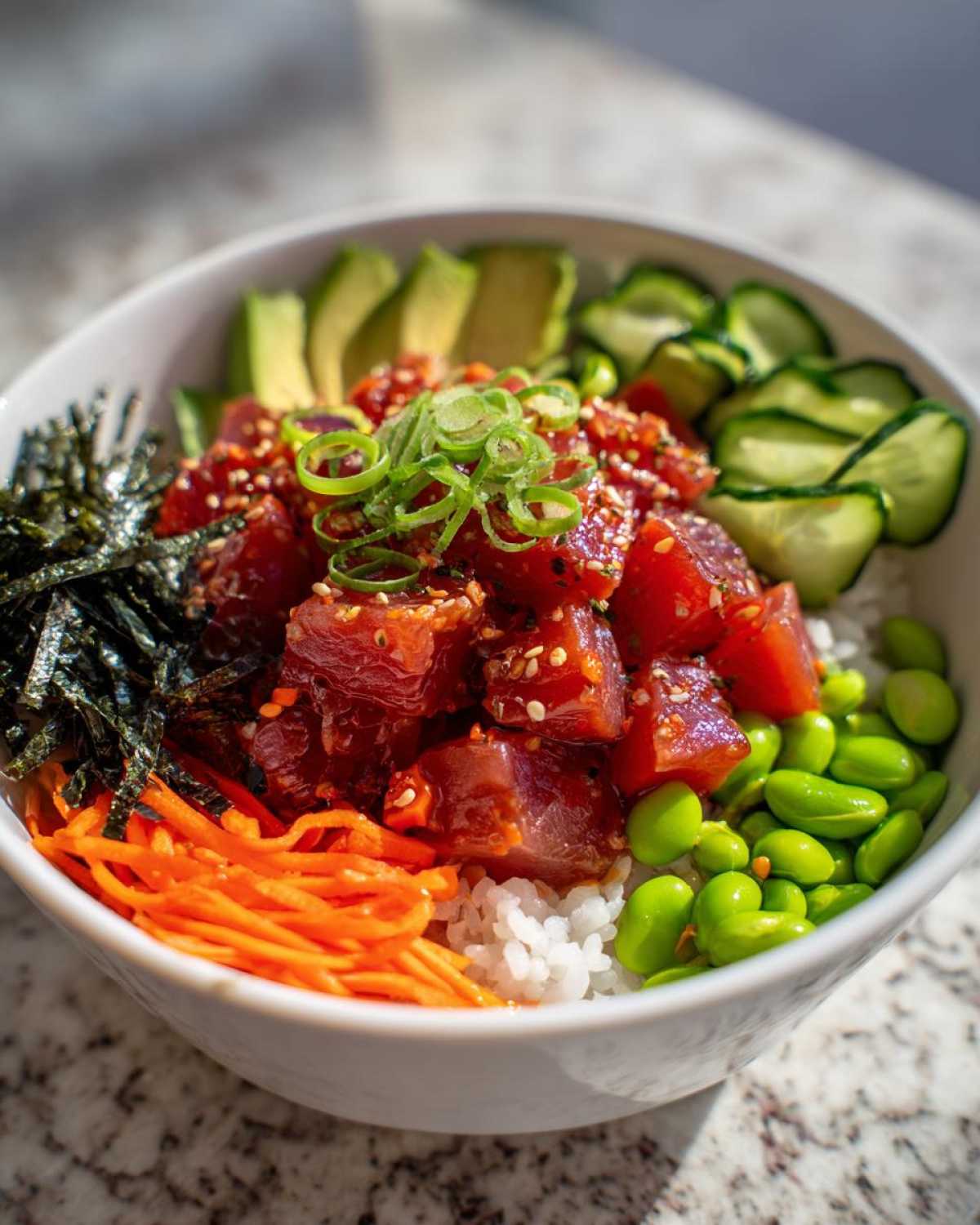 Close-up of a colorful Spicy Tuna Poke Bowl featuring marinated tuna, rice, avocado, cucumber, and edamame.