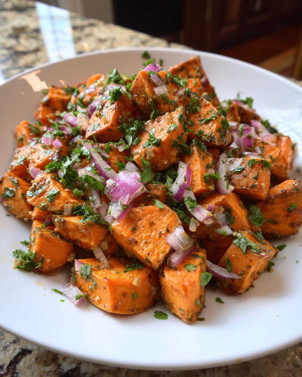 Close-up of a bright, flavorful sweet potato salad featuring diced orange sweet potatoes, red onion, and fresh parsley.