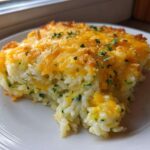 A generous serving of baked Zucchini and Rice Casserole topped with melted cheddar cheese and parsley.