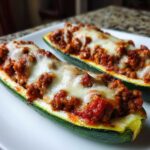 Two baked Zucchini Boats with Ground Turkey & Marinara filling topped with melted mozzarella cheese.